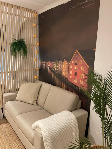a couch in a room with a painting on the wall at Studioleilighet midt i Trondheim in Lii