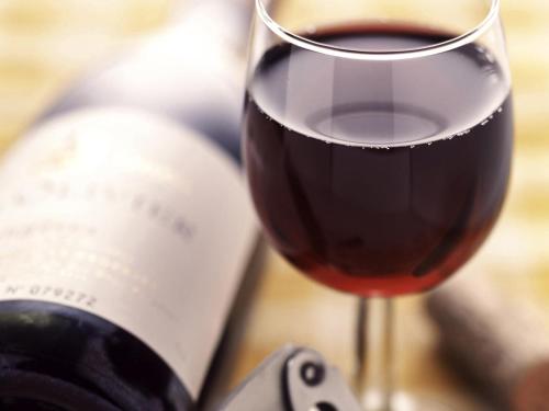 a glass of red wine next to a bottle of wine at Ibis Sheffield City in Sheffield