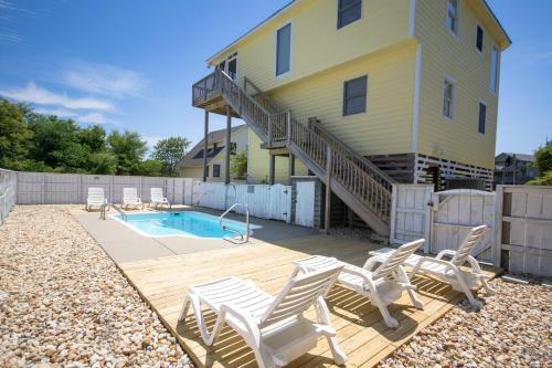 a backyard with a pool and chairs and a house at Shore Is Fun in Duck