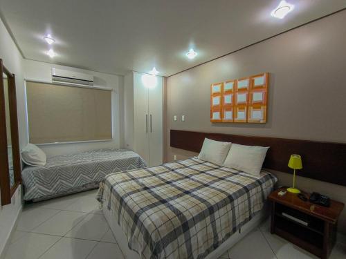 a hotel room with two beds and a window at Quarto e Sala completo com Cozinha, Ar condicionado, Wifi e Camareira in Salvador