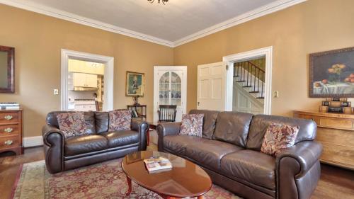 a living room with two leather couches and a table at Historic 98 Fire Pit Game Room & Dog Friendly in Geneva