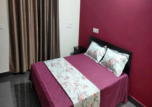 a bedroom with a bed with a purple wall at Samuels Comfort Homes in Bengaluru