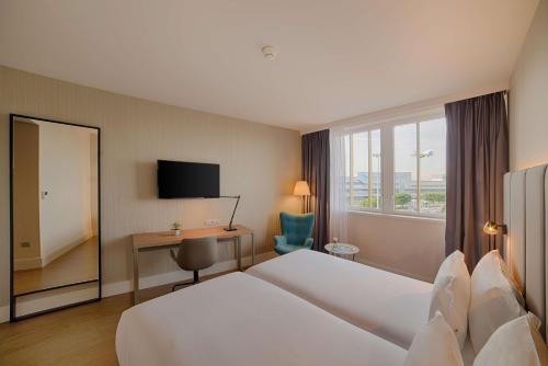 a hotel room with a bed and a desk and a window at NH Toulouse Airport in Blagnac