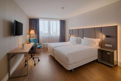 a hotel room with a large bed and a desk at NH Toulouse Airport in Blagnac