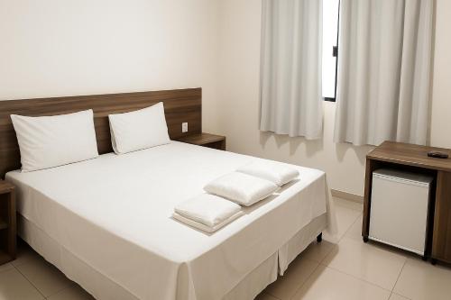 a bedroom with a large white bed with white pillows at Benni Palace Hotel in Parauapebas