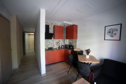 een keuken met oranje kasten en een tafel in een kamer bij Coloris Rubrum room in Thessaloniki