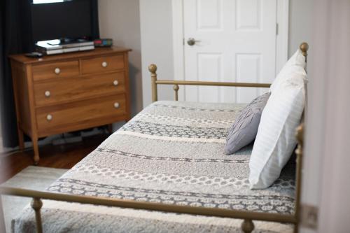 a bed with two pillows and a dresser with a door at Cityside Escape Spacious with Game Room & Fire Pit in Geneva