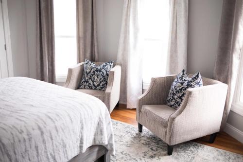 two chairs and a bed in a room with windows at Cityside Escape Spacious with Game Room & Fire Pit in Geneva