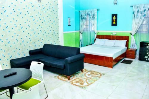 a room with a bed and a couch and a table at 5 Star Villa Hotel in Accra
