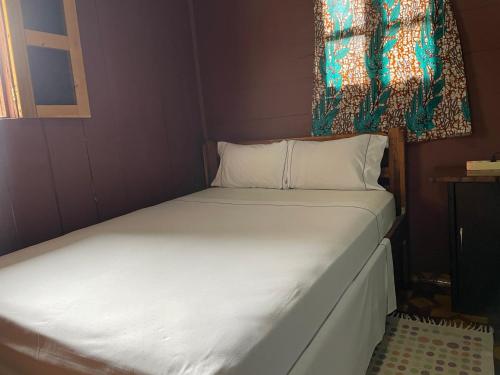 a small bedroom with a bed with white sheets and a window at Casas Salomão in Santo António
