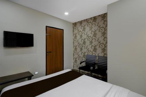 a bedroom with a bed and a tv and a chair at Hotel O The Pramaan in Kukatpalli