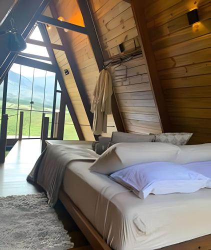two beds in a room with a large window at Cabana Zé da Lapinha - Passarela in Santana do Riacho