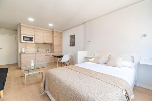 Un dormitorio con una gran cama blanca y una cocina. en Estudio Vigo by Plaza España, en Vigo