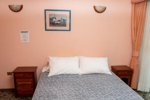 a bedroom with a bed with two night stands and two tables at Hotel Terranort in Iquique