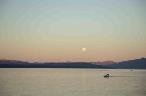 a boat on the water with the moon in the sky at La Cascada Casa Patagónica by DON in San Carlos de Bariloche