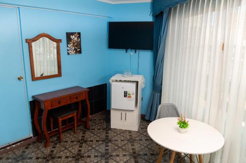 a room with a desk and a table and a refrigerator at Hotel Terranort in Iquique
