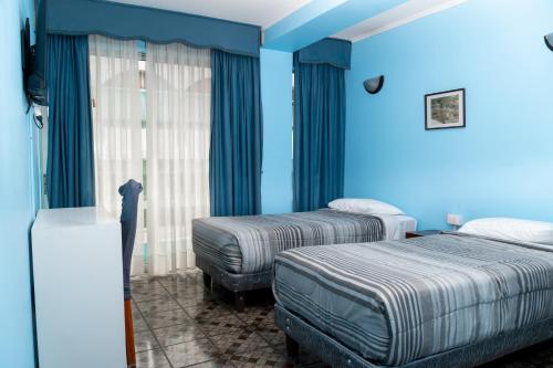 two beds in a room with blue walls at Hotel Terranort in Iquique