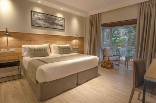 a bedroom with a large bed with a desk and a window at La Cascada Casa Patagónica by DON in San Carlos de Bariloche