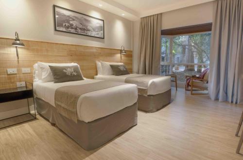 a hotel room with two beds and a balcony at La Cascada Casa Patagónica by DON in San Carlos de Bariloche