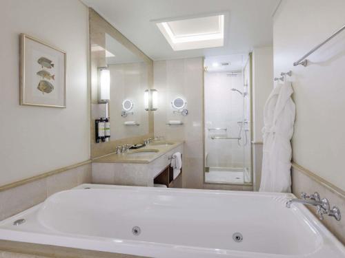 a large white bathroom with a tub and a sink at Pullman Reef Hotel Casino in Cairns