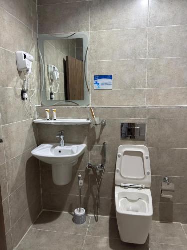 a bathroom with a sink and a toilet and a mirror at شقق دفادف المخدومة in Hail