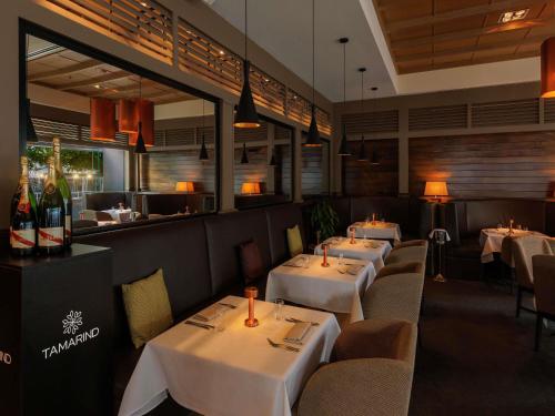 a restaurant with white tables and chairs and a bar at Pullman Reef Hotel Casino in Cairns