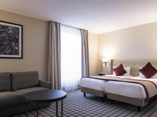 a hotel room with a bed and a couch at Mercure Luxembourg Kikuoka Golf & Spa in Canach