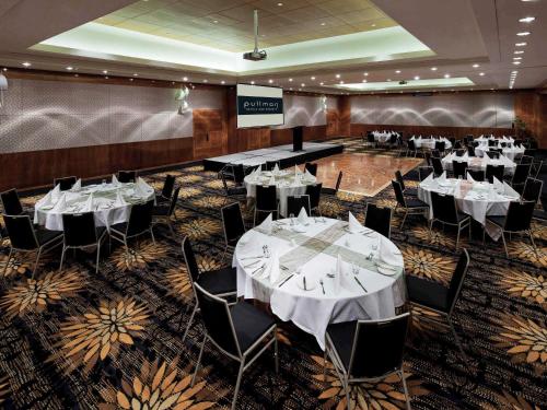 a banquet hall with white tables and chairs at Pullman Reef Hotel Casino in Cairns