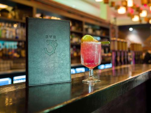 a drink sitting on a bar with a book at Pullman Reef Hotel Casino in Cairns