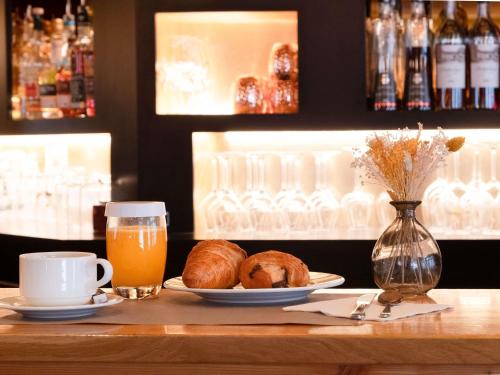 a table with a plate of bread and a cup of orange juice at Mercure Saint-Lary in Saint-Lary-Soulan