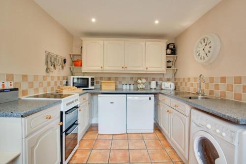 a kitchen with white cabinets and a tile floor at 2 Carr Terrace in Docking