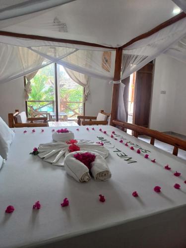 a bed with pink roses and towels on it at Sailorvilla and apartments in Jambiani