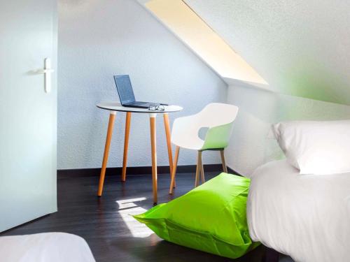 a bedroom with a laptop on a table with a chair at ibis Strasbourg Sud La Vigie in Ostwald