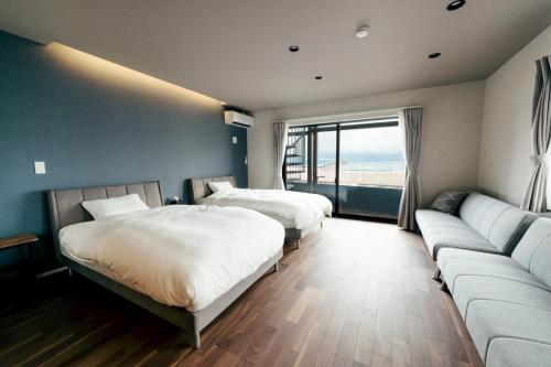 a hotel room with two beds and a couch at Kamogawa Sea Sauna Villa Kaito - Vacation STAY 08186v in Kamogawa