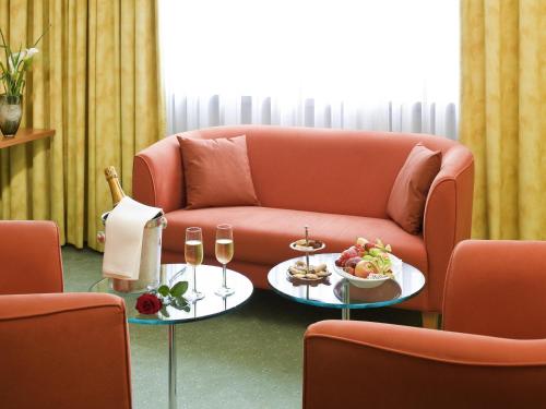 a living room with a couch and a table with food and wine at Mercure Hotel am Messeplatz Offenburg in Offenburg
