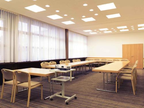 a large room with tables and chairs and windows at Mercure Hotel am Messeplatz Offenburg in Offenburg