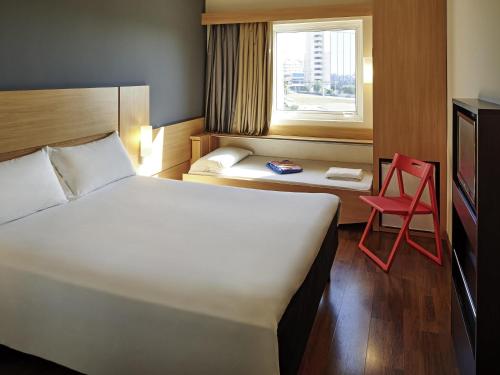 a hotel room with a bed and a red chair at ibis Sorocaba in Sorocaba