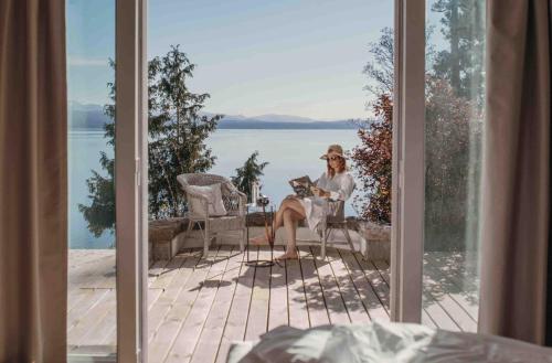 a woman sitting on a porch with a dog at La Cascada Casa Patagónica by DON in San Carlos de Bariloche