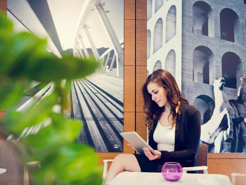 a woman sitting at a table using a tablet at Mercure Roma Centro Colosseo in Rome
