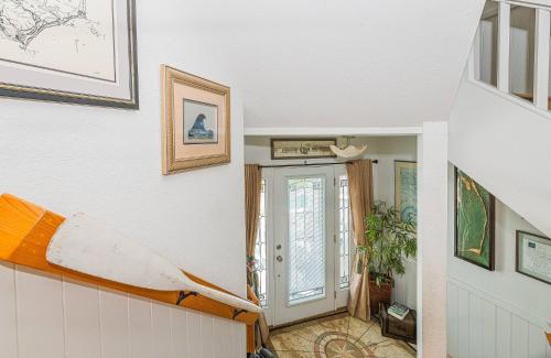 a room with a staircase with a surfboard on the wall at Simple Gifts by the Sea in Duck