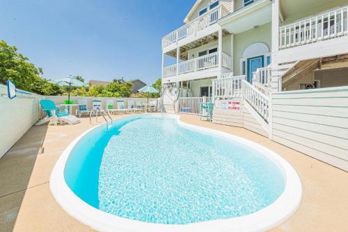 a swimming pool in front of a building at Simple Gifts by the Sea in Duck
