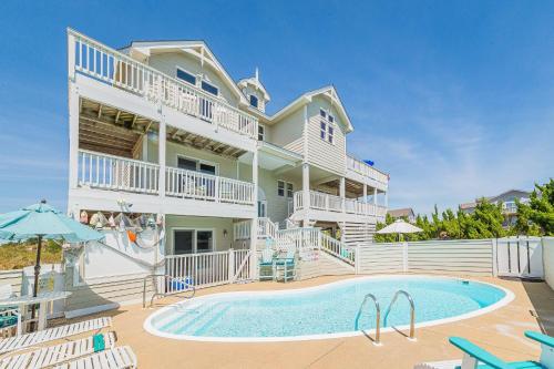 a large house with a swimming pool in front of it at Simple Gifts by the Sea in Duck