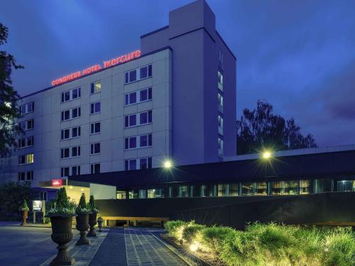 a white building with a red sign on it at Congress Hotel Mercure Nürnberg an der Messe in Nürnberg