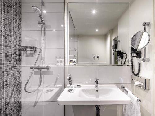 a white bathroom with a sink and a shower at Congress Hotel Mercure Nürnberg an der Messe in Nürnberg
