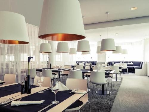a restaurant with tables and white chairs and lights at Congress Hotel Mercure Nürnberg an der Messe in Nürnberg