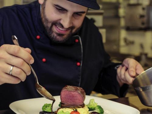 a man eating a plate of food with a fork at Congress Hotel Mercure Nürnberg an der Messe in Nürnberg