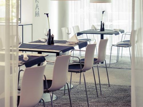 a dining room with black tables and white chairs at Congress Hotel Mercure Nürnberg an der Messe in Nürnberg