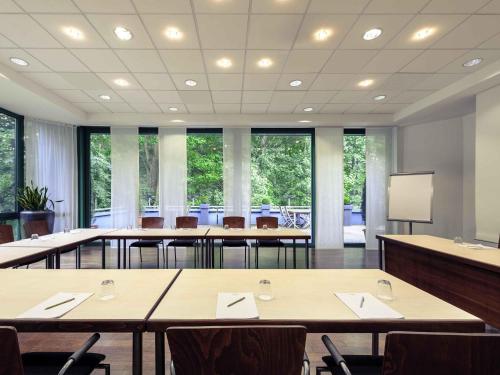 a conference room with tables and chairs and windows at Congress Hotel Mercure Nürnberg an der Messe in Nürnberg