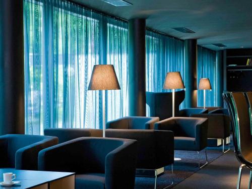 a waiting room with blue chairs and large windows at Congress Hotel Mercure Nürnberg an der Messe in Nürnberg