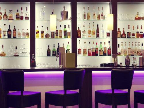 a bar with purple stools and bottles of alcohol at Mercure Hotel Hagen in Hagen